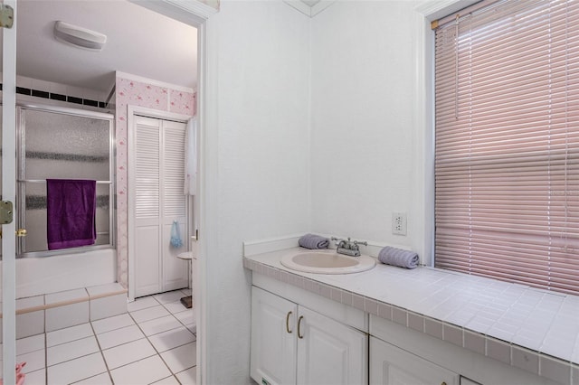 bathroom with tile patterned flooring, vanity, and combined bath / shower with glass door