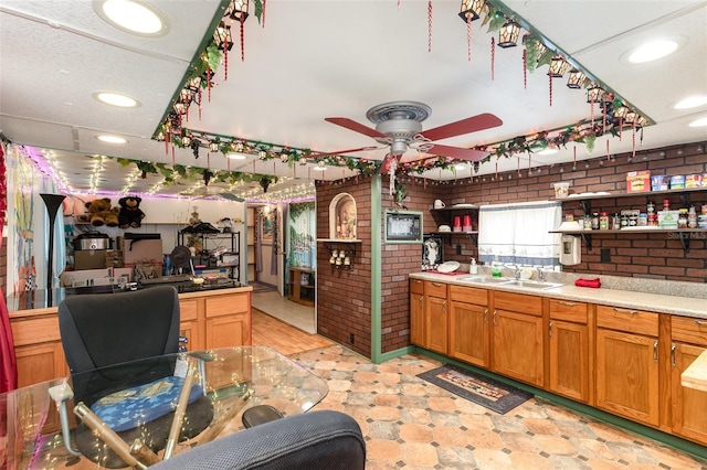 kitchen featuring sink, ceiling fan, and brick wall