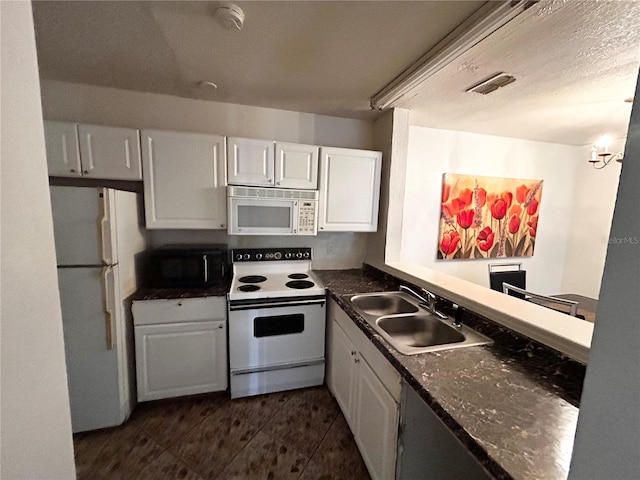 kitchen with white cabinetry, dark stone countertops, white appliances, and sink