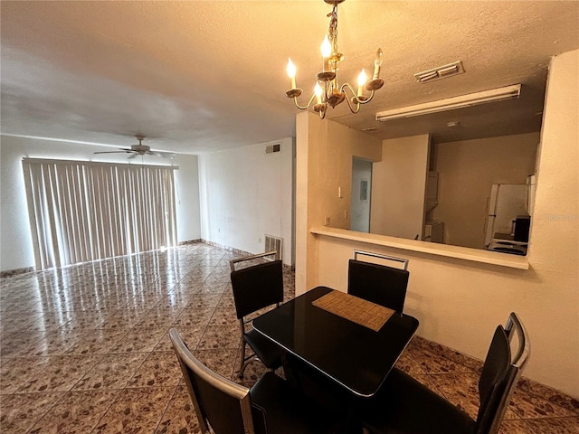 dining space featuring ceiling fan with notable chandelier and a textured ceiling