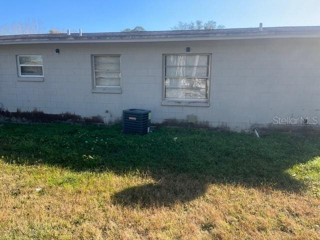 view of property exterior with a yard and central AC