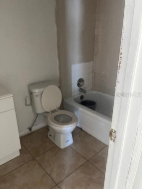 bathroom with tile patterned floors, a tub, and toilet