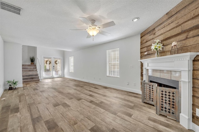 unfurnished living room featuring a fireplace, a textured ceiling, light hardwood / wood-style floors, and ceiling fan