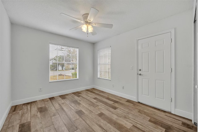 empty room featuring ceiling fan, light hardwood / wood-style flooring, and a textured ceiling