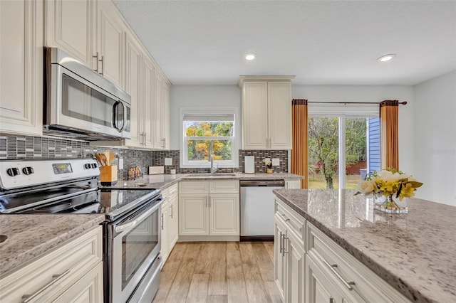 kitchen with plenty of natural light, appliances with stainless steel finishes, light wood-type flooring, and a sink