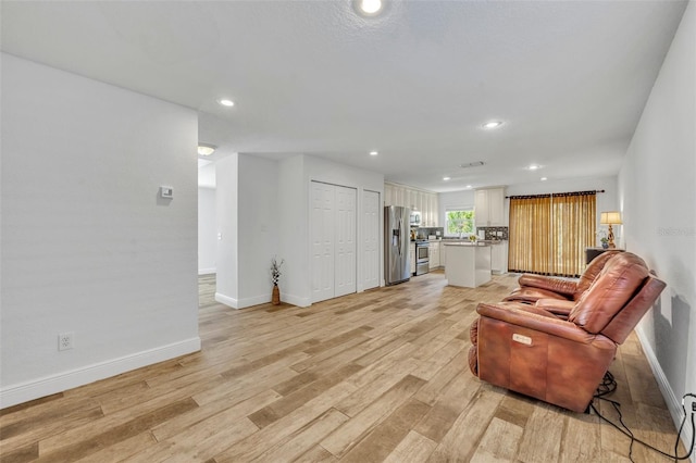 living area featuring visible vents, recessed lighting, light wood-style floors, and baseboards