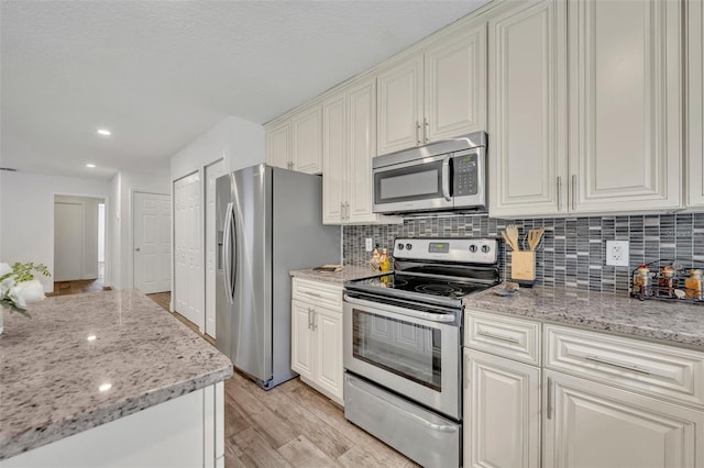 kitchen featuring light stone countertops, decorative backsplash, recessed lighting, light wood-style floors, and stainless steel appliances