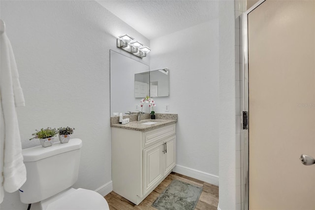 full bathroom with vanity, wood finished floors, baseboards, a shower stall, and toilet