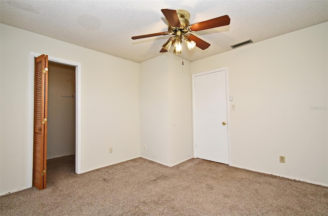 spare room with ceiling fan, a textured ceiling, and light carpet