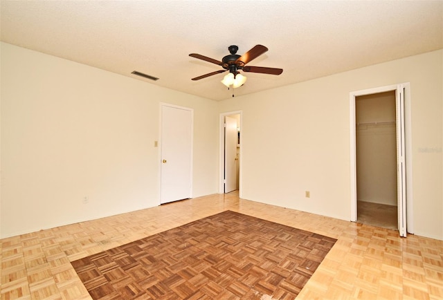 unfurnished room with ceiling fan, light parquet floors, and a textured ceiling