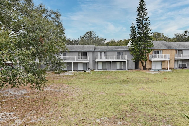 back of house featuring a lawn and a balcony