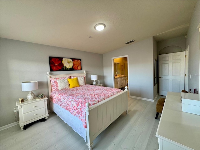 bedroom featuring connected bathroom and light hardwood / wood-style floors