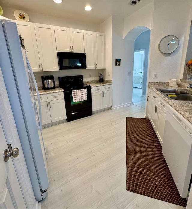 kitchen featuring white cabinetry, sink, light stone counters, light hardwood / wood-style flooring, and black appliances