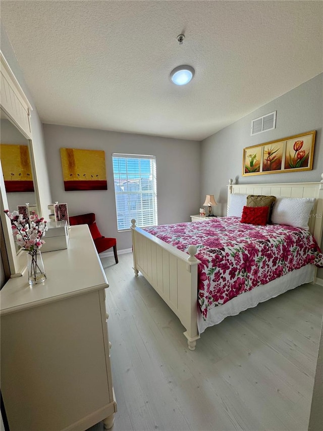 bedroom with light hardwood / wood-style flooring and a textured ceiling