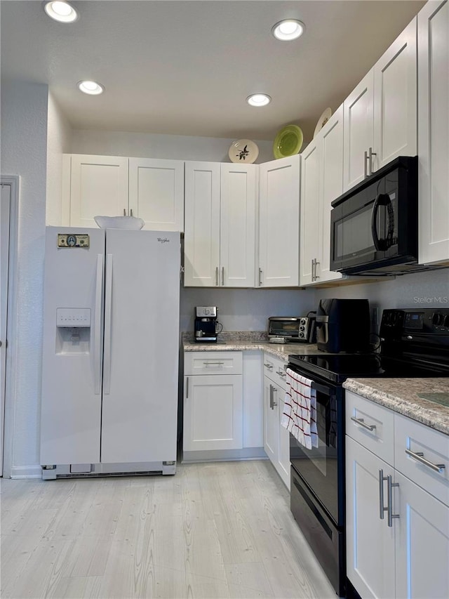 kitchen with light stone countertops, light hardwood / wood-style flooring, white cabinetry, and black appliances