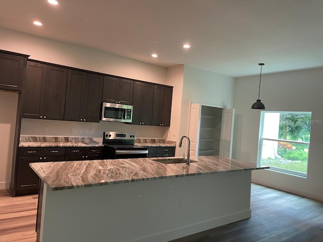 kitchen featuring appliances with stainless steel finishes, an island with sink, decorative light fixtures, and sink