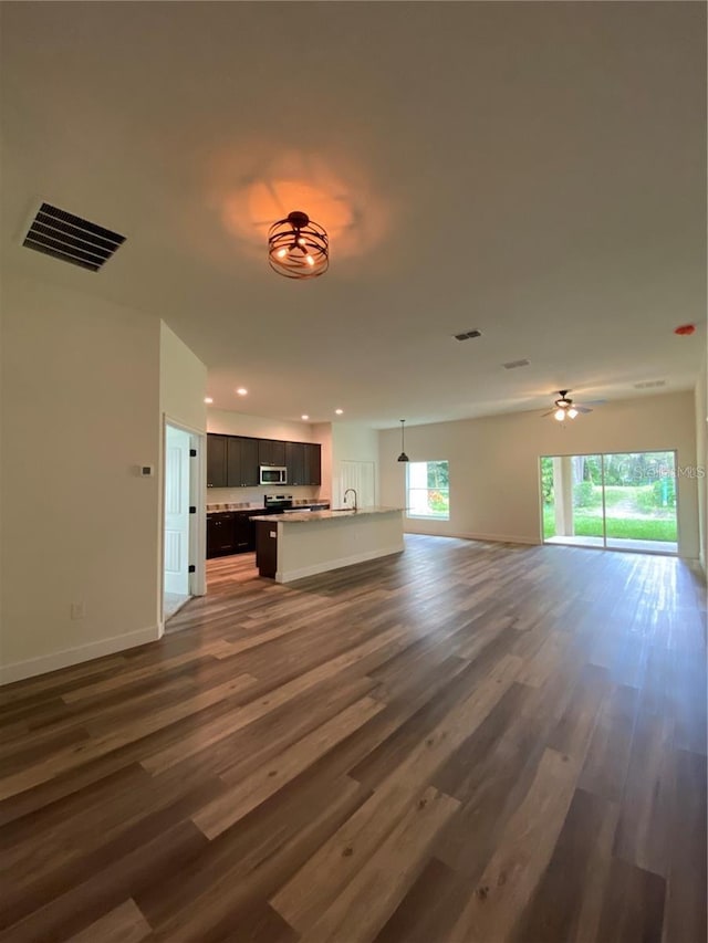 unfurnished living room with ceiling fan, sink, and dark wood-type flooring