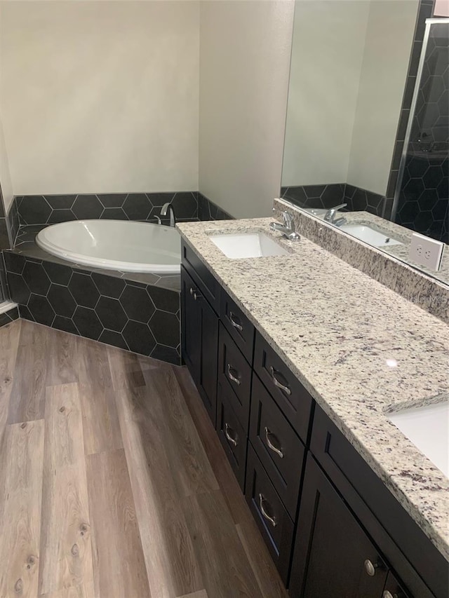 bathroom with tiled bath, vanity, and hardwood / wood-style flooring