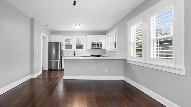 kitchen featuring kitchen peninsula, white cabinetry, dark wood-type flooring, and appliances with stainless steel finishes