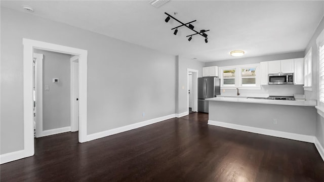 kitchen featuring dark hardwood / wood-style flooring, white cabinetry, kitchen peninsula, and appliances with stainless steel finishes