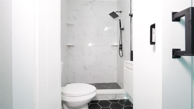 bathroom with tile patterned floors, toilet, and tiled shower