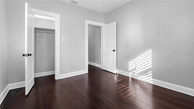 unfurnished bedroom with a closet and dark hardwood / wood-style floors