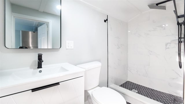 bathroom featuring a tile shower, vanity, toilet, and lofted ceiling