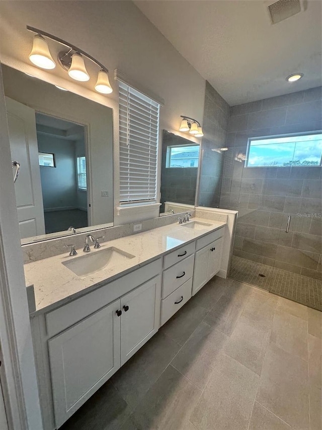 bathroom with tile patterned flooring, vanity, and a tile shower