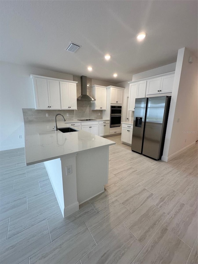 kitchen featuring sink, appliances with stainless steel finishes, white cabinets, kitchen peninsula, and wall chimney exhaust hood