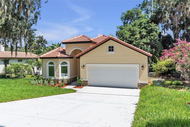 mediterranean / spanish-style house with central AC unit, a garage, and a front lawn