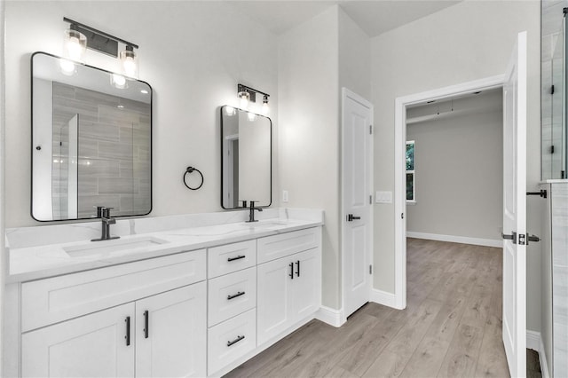 bathroom with a tile shower, vanity, and hardwood / wood-style flooring