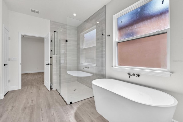 bathroom featuring separate shower and tub and wood-type flooring