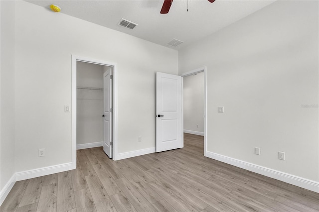 unfurnished bedroom with a walk in closet, ceiling fan, a closet, and light hardwood / wood-style floors