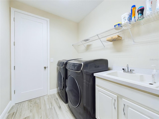 laundry room featuring washing machine and dryer, sink, and cabinets