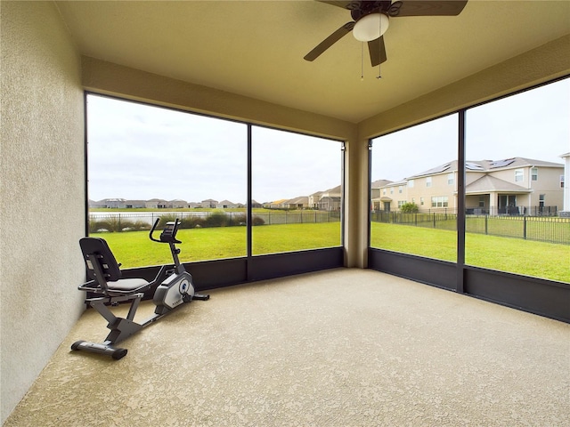 sunroom / solarium with a water view, ceiling fan, and a healthy amount of sunlight