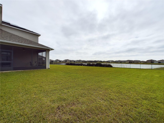 view of yard with a sunroom and a water view