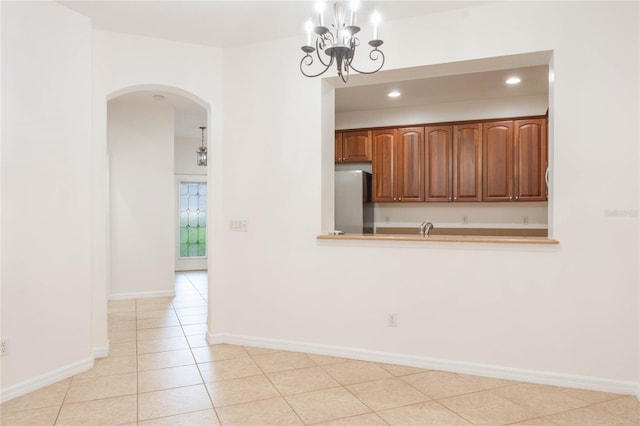 empty room featuring a chandelier, light tile patterned floors, and sink