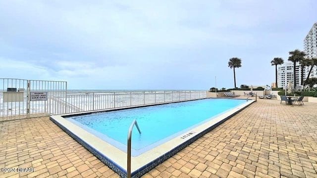 view of pool featuring a patio area and a water view