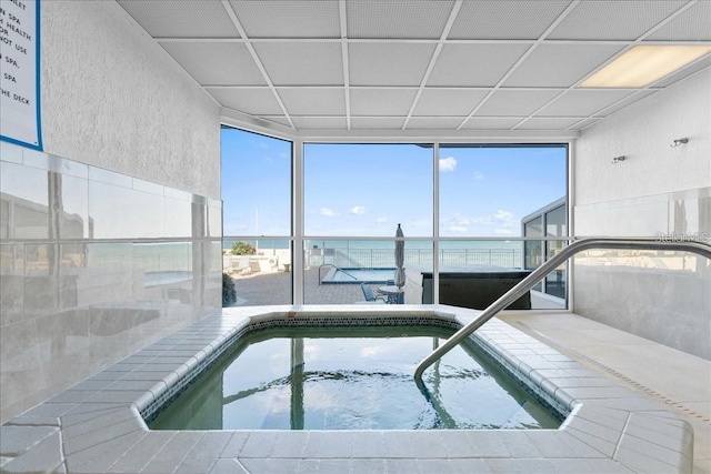 view of swimming pool featuring an indoor in ground hot tub and a water view