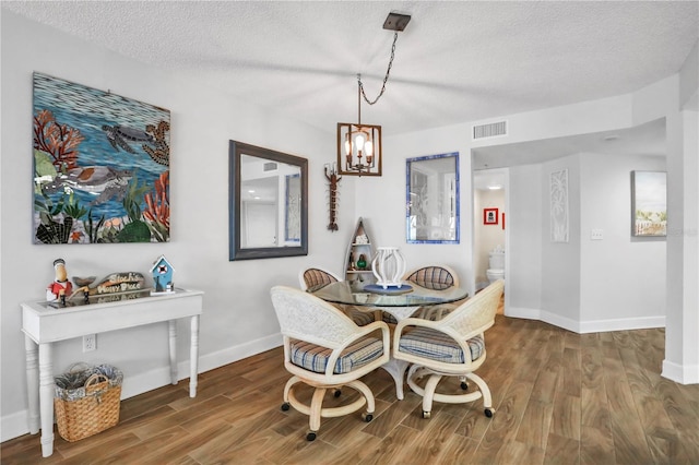 dining room with hardwood / wood-style flooring, a notable chandelier, and a textured ceiling