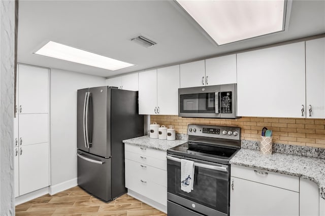 kitchen featuring tasteful backsplash, light hardwood / wood-style floors, light stone counters, white cabinetry, and stainless steel appliances