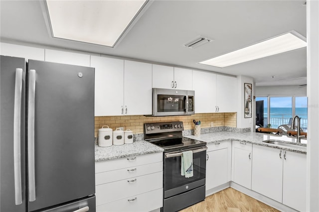 kitchen with a water view, sink, light hardwood / wood-style floors, white cabinetry, and stainless steel appliances