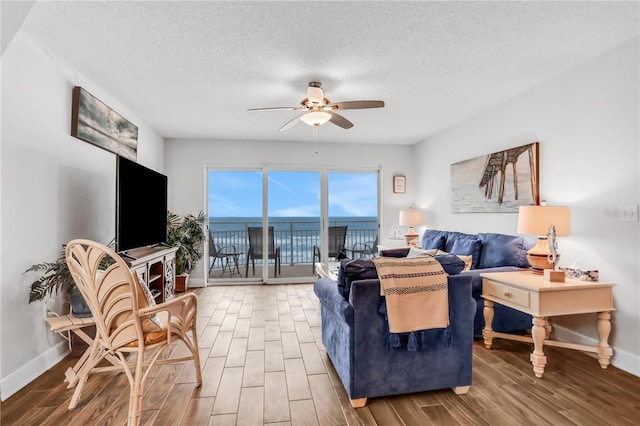 living room featuring ceiling fan, hardwood / wood-style floors, and a textured ceiling