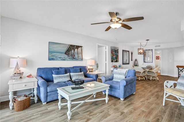 living room featuring a textured ceiling, ceiling fan with notable chandelier, and hardwood / wood-style flooring