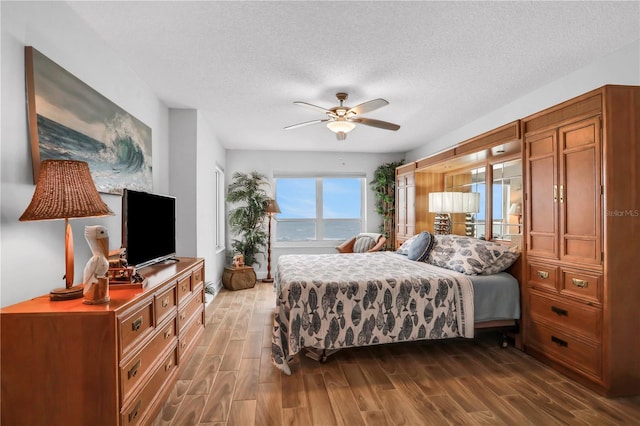 bedroom with ceiling fan, dark hardwood / wood-style flooring, and a textured ceiling