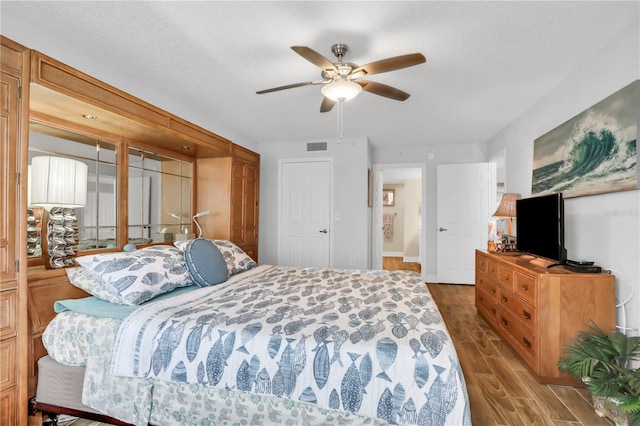 bedroom featuring ceiling fan, dark hardwood / wood-style flooring, and a textured ceiling