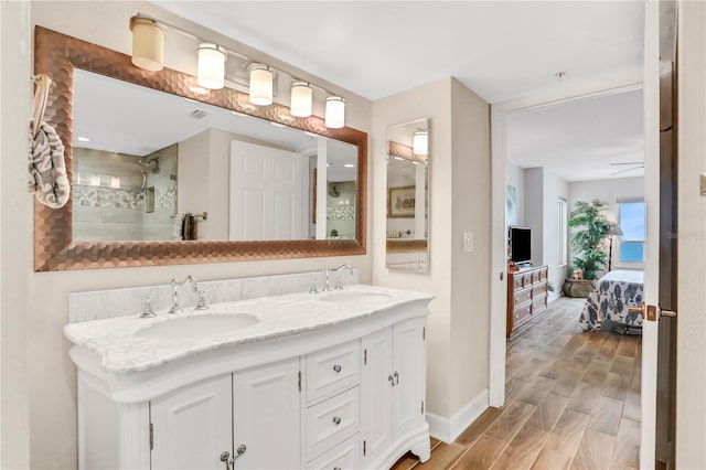 bathroom with vanity, ceiling fan, wood-type flooring, and tiled shower