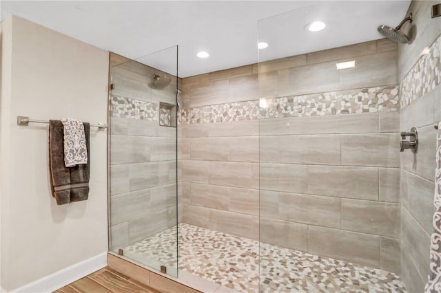 bathroom with tiled shower and hardwood / wood-style flooring