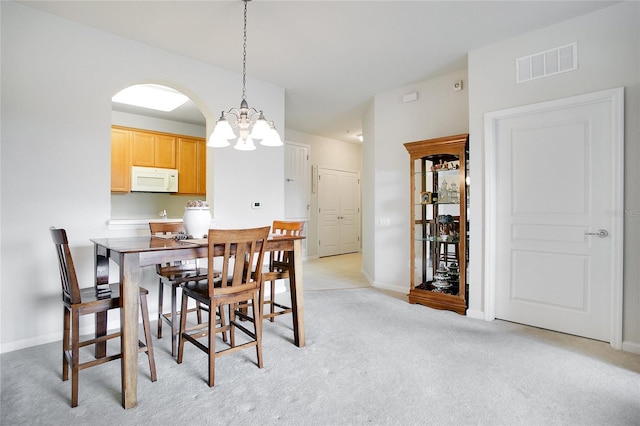 carpeted dining room featuring a notable chandelier