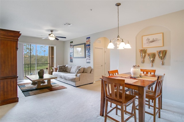 carpeted dining space featuring ceiling fan with notable chandelier